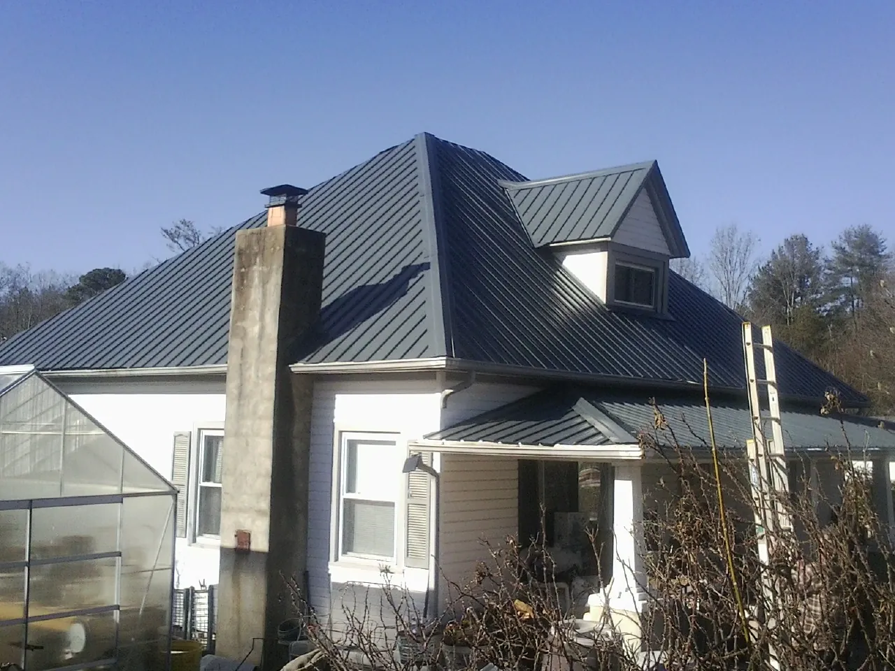 Dark blue standing seam metal roof on a white farmhouse with dormer — Slate & Tile Roof Repair by Roofing Brothers in Pope Army Airfield