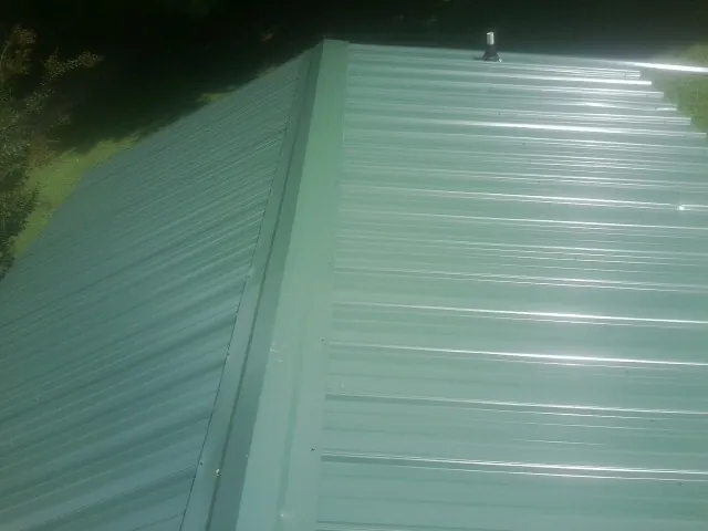 New green metal panels meeting at the ridge of a roof — Flat Roof Repair work by our crew in Pope Army Airfield