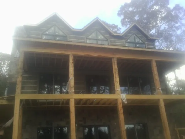 Dormers and porch framing on a large log home under construction — Roof Coating work by our crew in Pope Army Airfield