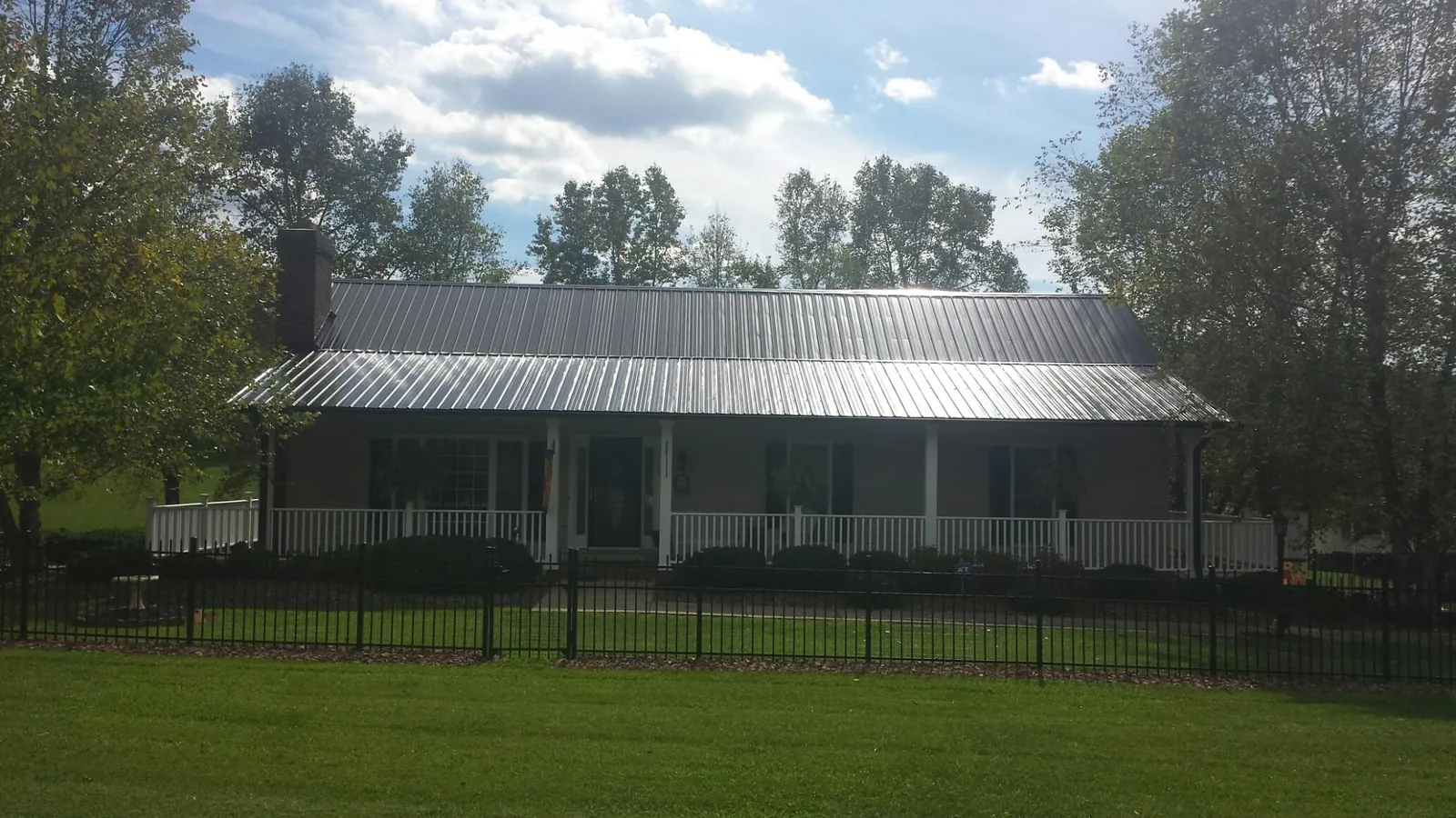 Gray metal roof on a brick ranch with a full width front porch — Gutter Guard Installation work by our crew in Pope Army Airfield